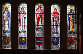 Blick vom Altarraum auf die Orgelempore: Die Fenster zeigen in der Mitte Christus, links und rechts die vier Evangelisten