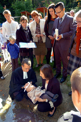 Klein war der Bach geworden, aber für die acht Taufen reichte das Wasser gerade noch. Hier wird Mila Emmerich auf dem Arm ihrer Mutter Stefanie getauft, dahinter Vater Julian Neumann mit der Taufkerze.