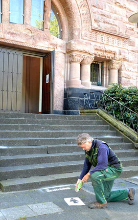 Kirchmeister Christian Gerlemann sprüht Engel als Abstandshalter im Eingangsbereich vor der Kirche auf den Boden.